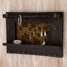 a wooden shelf with rings and other items on it in the shape of a wall hanging