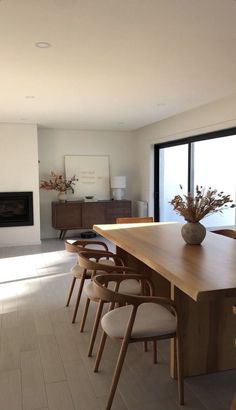 a dining room table with chairs and a vase filled with flowers sitting on top of it