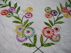 an embroidered table cloth with colorful flowers on it