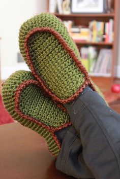 someone's feet wearing knitted slippers on top of a table