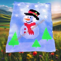 a crocheted snowman is in the middle of a field with trees and flowers