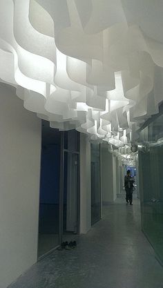 a person walking down a long hallway with lots of lights hanging from it's ceiling