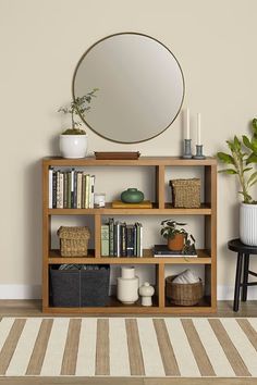 a bookshelf filled with lots of books next to a round mirror on the wall