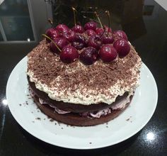 a chocolate cake topped with cherries on top of a white plate