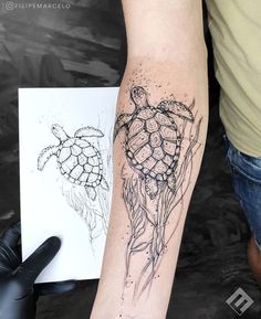 a person with a tattoo on their arm holding a piece of paper next to a drawing