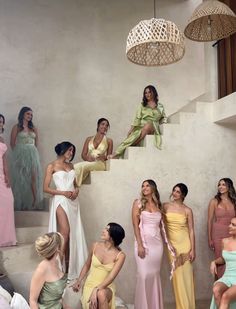 a group of women standing around each other in front of a staircase with dresses on