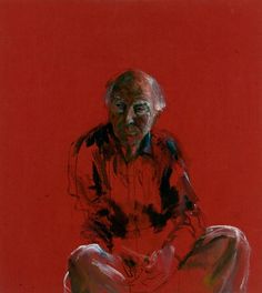 an older man sitting on the ground in front of a red wall