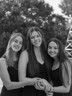 three young women standing next to each other in front of a ferris wheel at an amusement park