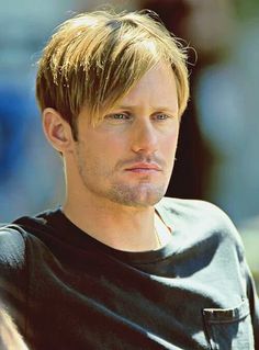 a close up of a person wearing a black t - shirt and looking at the camera