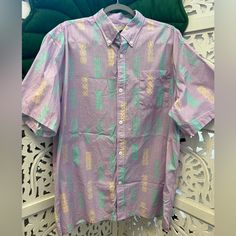 a purple shirt with green pineapples on it is hanging on a white wall