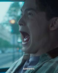 a man is screaming in the back seat of a car with his mouth wide open