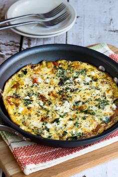 an omelet with spinach and cheese in a pan on a cutting board