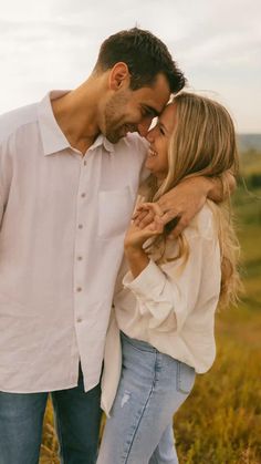 a man and woman are standing together in the grass with their arms around each other