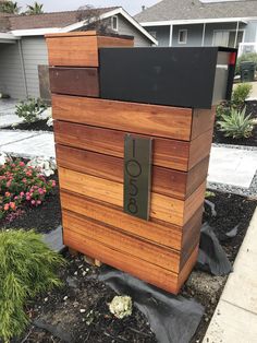 a wooden box with a sign on it sitting in the middle of a flower bed