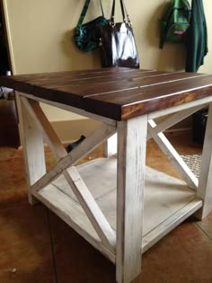 a wooden table sitting on top of a tile floor next to a handbag and purse