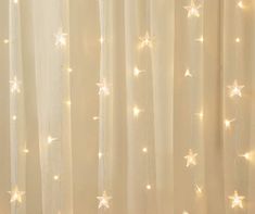 a curtain with white stars on it in front of a light filled wall and window