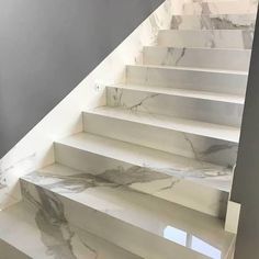 marble steps leading up to the top of a stair case in a house with grey walls