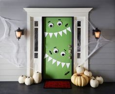 a green door decorated with monster faces and pumpkins