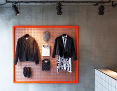 clothes and shoes are displayed on an orange mesh display in the corner of a room