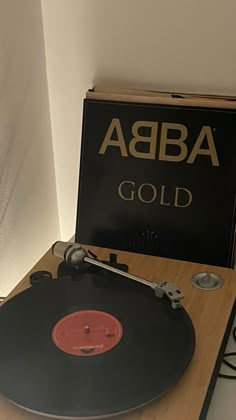 an old record player sitting on top of a wooden table next to a sign that says abba gold