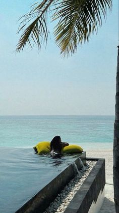 a person laying on top of a yellow surfboard in the ocean next to a palm tree