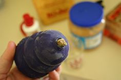 a hand holding a blue object with some peanut butter on the top and other ingredients in the background