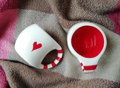 two cups with red liquid in them sitting on a blanket next to a cup holder