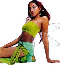 a beautiful young woman sitting on the ground wearing a green skirt and fairy costume with wings