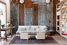 a living room filled with furniture and lots of bookshelves in front of a wooden wall