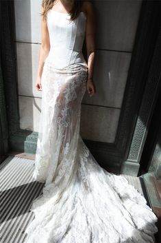 a woman in a white dress leaning against a wall