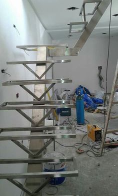 an unfinished room with metal stairs and tools on the floor in front of it that is being worked on