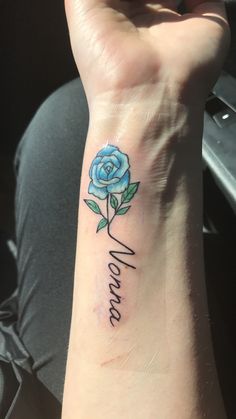 a small blue rose tattoo on the wrist