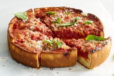 a deep dish pizza with cheese and basil on top, cut into four pieces to be served