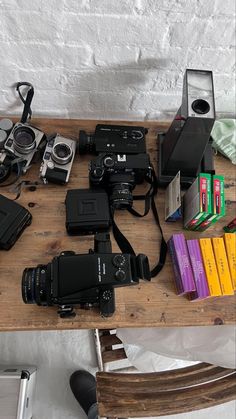 a wooden table topped with cameras and books