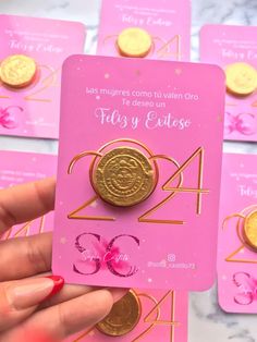 a person holding up a pink card with gold numbers and coins in front of them