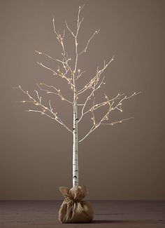 a small white tree with lights on it and a brown bag in front of it