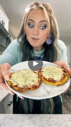 a woman is holding two pizzas on a plate