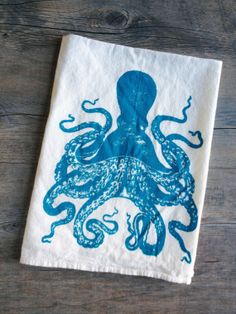 an octopus tea towel on a wooden table with blue ink drawn on it's face