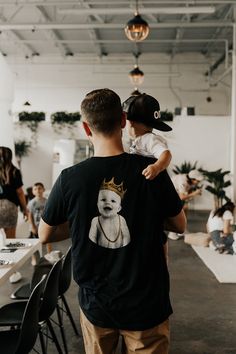 a man holding a baby wearing a crown on his head while standing in an office