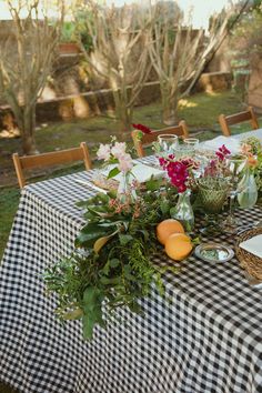 the table is set with flowers, fruit and wine glasses on it for an outdoor dinner