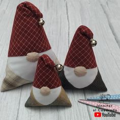 three gnomes sitting on top of each other in red and white fabric with bells