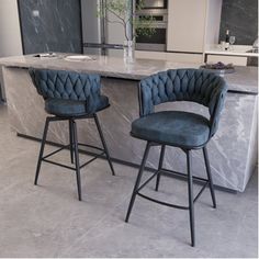 two blue velvet bar stools in front of an island with marble countertop and stainless steel barstools