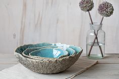 three bowls sitting on top of a table next to a vase with flowers in it