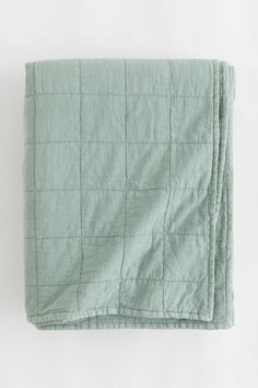 a green blanket is folded up on a white surface