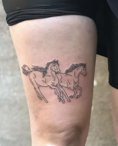 a woman's leg with a tattoo of two horses on the side of her thigh