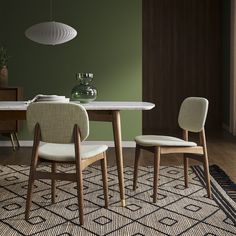 a dining room table with two chairs and a rug on the floor