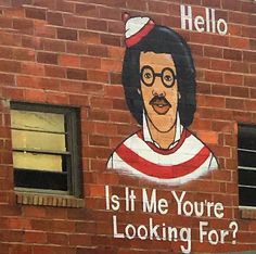 a brick building with a painted mural on it's side that says, is it me you're looking for?