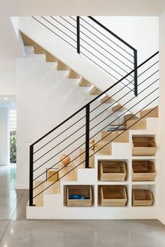 a stair case with baskets under the bannister and below it is an open staircase