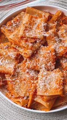 a white bowl filled with pasta covered in parmesan cheese