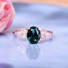 a blue ring with two white diamonds on it and a pink rose in the background